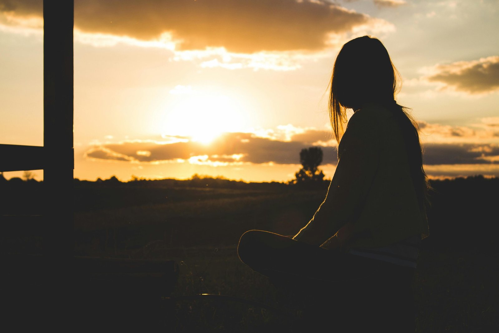 A serene silhouette of a woman meditating at sunset in the Romanian countryside.